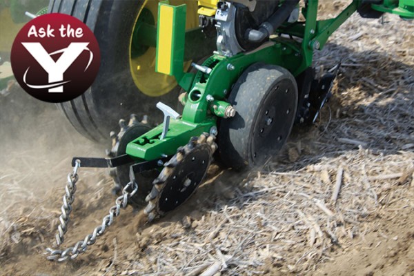 Closeup of Yetter Twister Closing Wheel with drag chain running in field on John Deere planter with Ask the Y logo